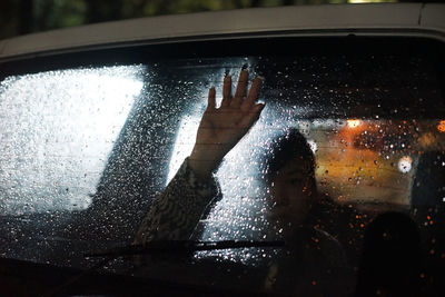 Woman seen through wet glass window