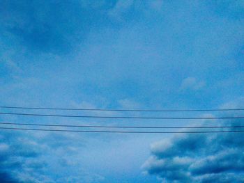 Low angle view of power lines against blue sky