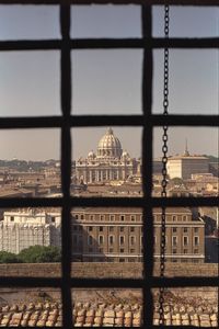 Buildings against sky seen through window