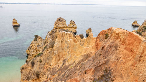 Rear view of man standing on rock by sea against sky