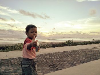 Boy standing on beach against sky