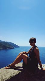 Portrait of woman sitting at beach against clear sky