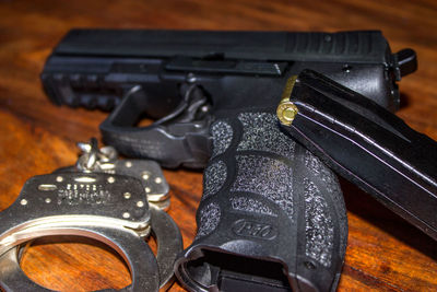 High angle view of gun with cuffs on table