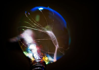 Close-up of illuminated spider web against black background