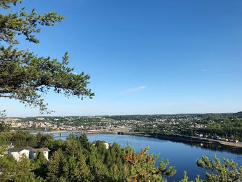 Scenic view of river by trees against blue sky