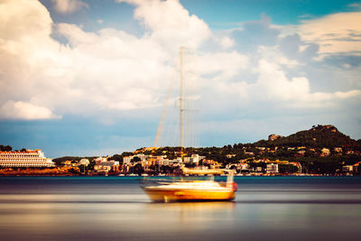 Sailboats in sea against cloudy sky