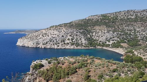 Scenic view of sea and mountains against clear blue sky