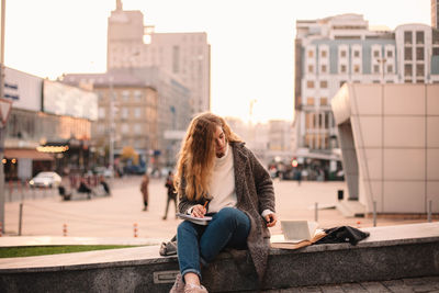 Teenage student girl studying while sitting at campus in autumn