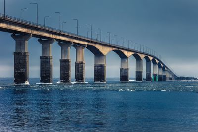 Low angle view of bridge over river against blue sky