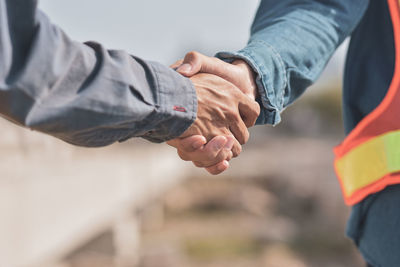 Close-up of coworkers shaking hands at construction site