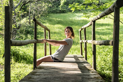 Fit woman sitting and relaxing on a wooden bridge in the middle