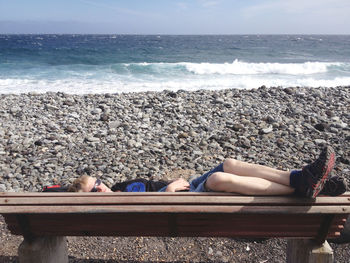 High angle view of woman relaxing on bench at shore