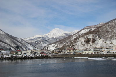 Scenic view of lake by snowcapped mountains against sky