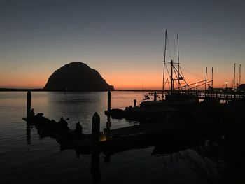 Silhouette sailboats in sea against clear sky during sunset