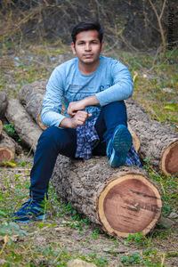 Portrait of young man sitting on wood