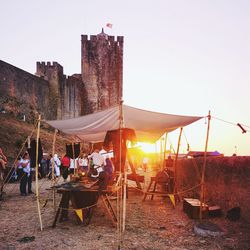 People at beach against clear sky during sunset