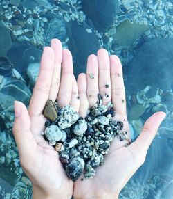 High angle view of hand holding pebbles