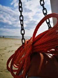 Close-up of swing hanging on rope at beach against sky