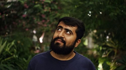 Portrait of young man looking away against plants