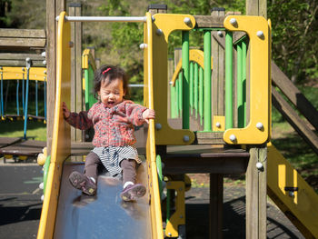 Baby girl playing on slide at playground