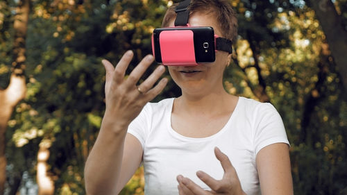 Woman using virtual reality simulator against trees