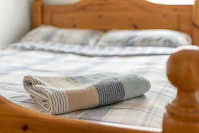 Towel rolled up on bed at home, wooden bed.