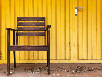 Empty bench against yellow wall
