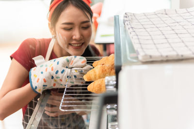 Smiling baker preparing bun at oven