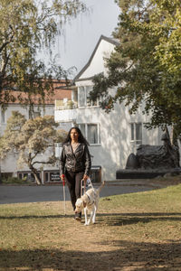 Visually impaired woman walking on lawn with guide dog