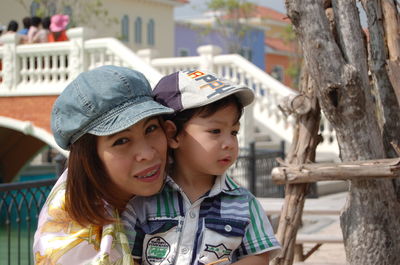 Close-up portrait of mother carrying son while standing on bridge