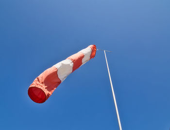Low angle view of windsock against clear blue sky