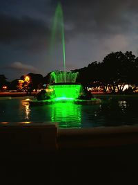 Illuminated fountain in park against sky at night