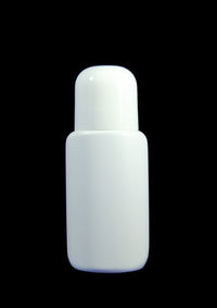 Close-up of white bottle against black background