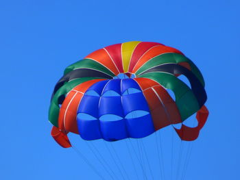 Low angle view of colorful parachute flying against clear sky