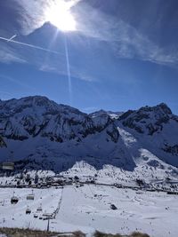 Scenic view of snow covered mountains against bright sun