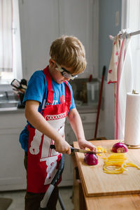 Boy cutting onion in kitchen at home