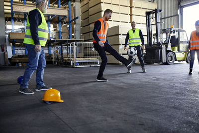 Workers playing football in factory warehouse