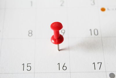 Close-up of red thumbtack on calendar