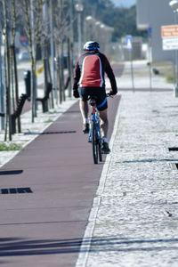 Rear view of man riding bicycle on street