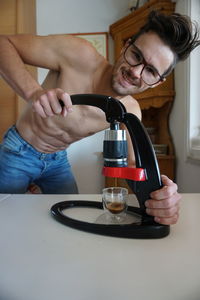 Portrait of shirtless man making coffee on kitchen island