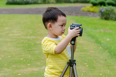 Cute boy photographing while standing at park