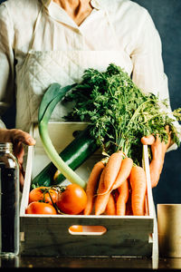 Midsection of woman with vegetables on table