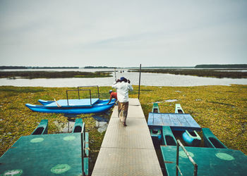 Rear view of man sitting on seat in lake against sky