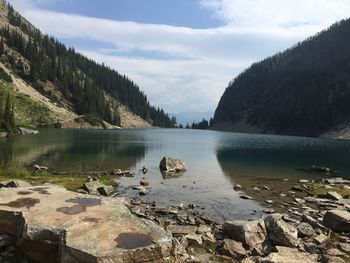 Scenic view of lake by stones against sky