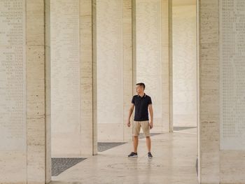 Full length of young man standing by columns at colonnade