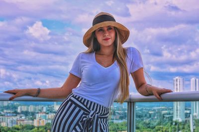 Portrait of young woman standing against sky