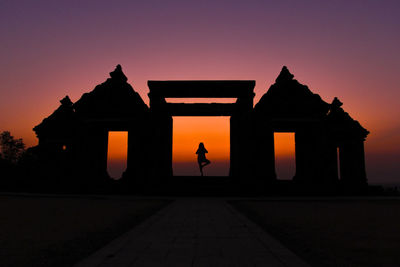 Silhouette person doing yoga at gateway of ratu boko ruins against clear sky