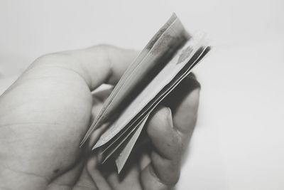 Close-up of hand holding paper currency over white background