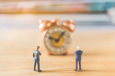 Close-up of figurines against clock on table