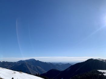 Scenic view of snowcapped mountains against blue sky